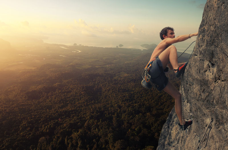 Bild zeigt einen jungen Mann beim Klettern im Sonnenuntergang. © Adobe Stock: Dudarev Mikhail