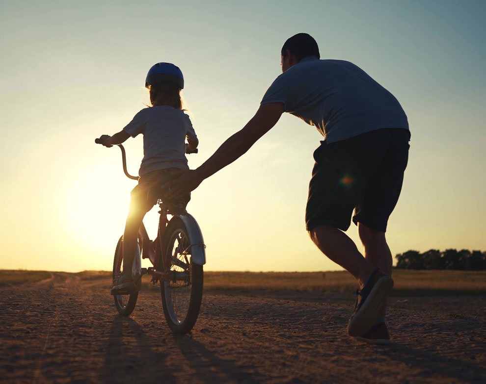 Bild zeigt einen Mann, der ein Fahrrad mit Kind anschiebt Bildnachweis: Adobe Stockmaxximmm